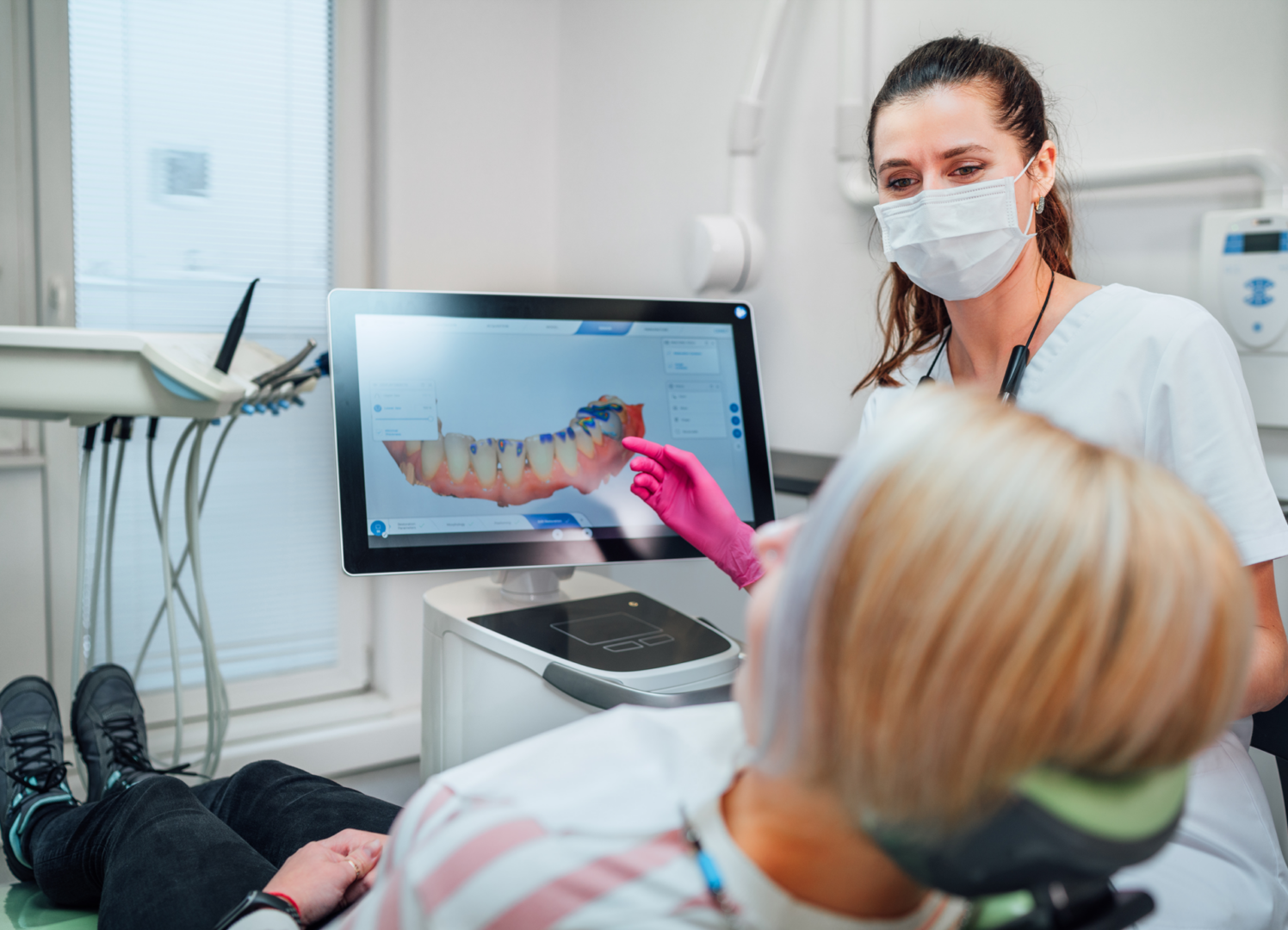 Dentist showing scan to patient on screen.