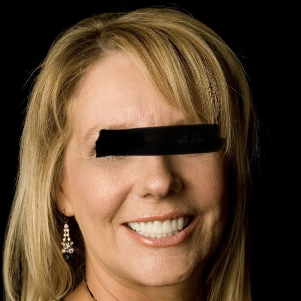 Smiling woman with black bar over eyes.