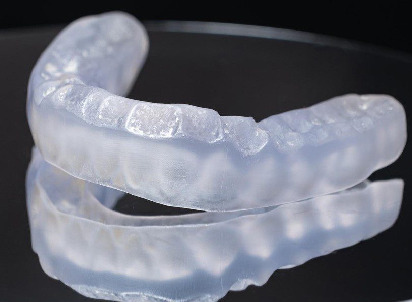 Clear dental aligners on reflective surface.